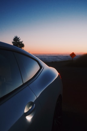 A sleek sedan parked on a scenic coastal road during sunset.