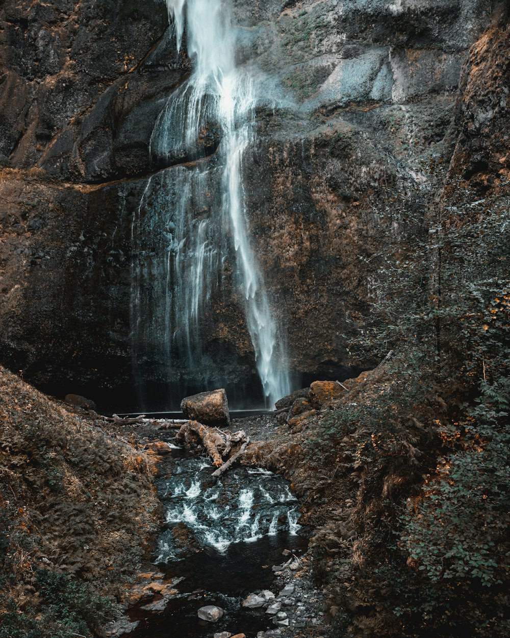 a waterfall is seen in the middle of a rocky area