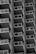 A series of repeating balconies on a tall building, each featuring metal railings and glass panels. The architectural design creates a geometric pattern with strong, clean lines and a sense of uniformity.