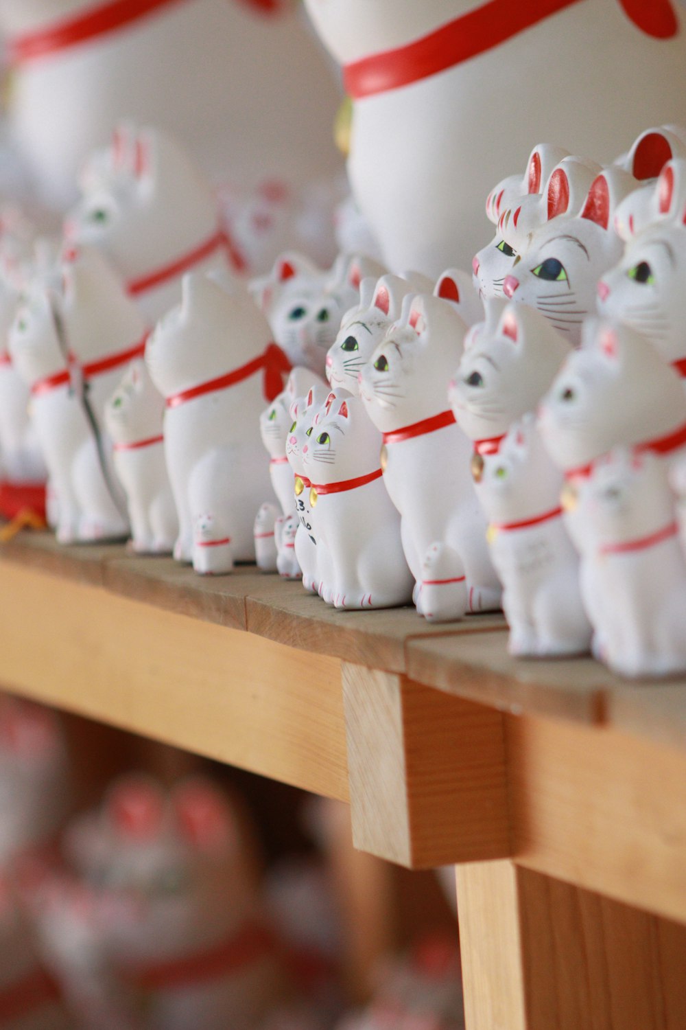 a row of white cat figurines sitting on top of a wooden table