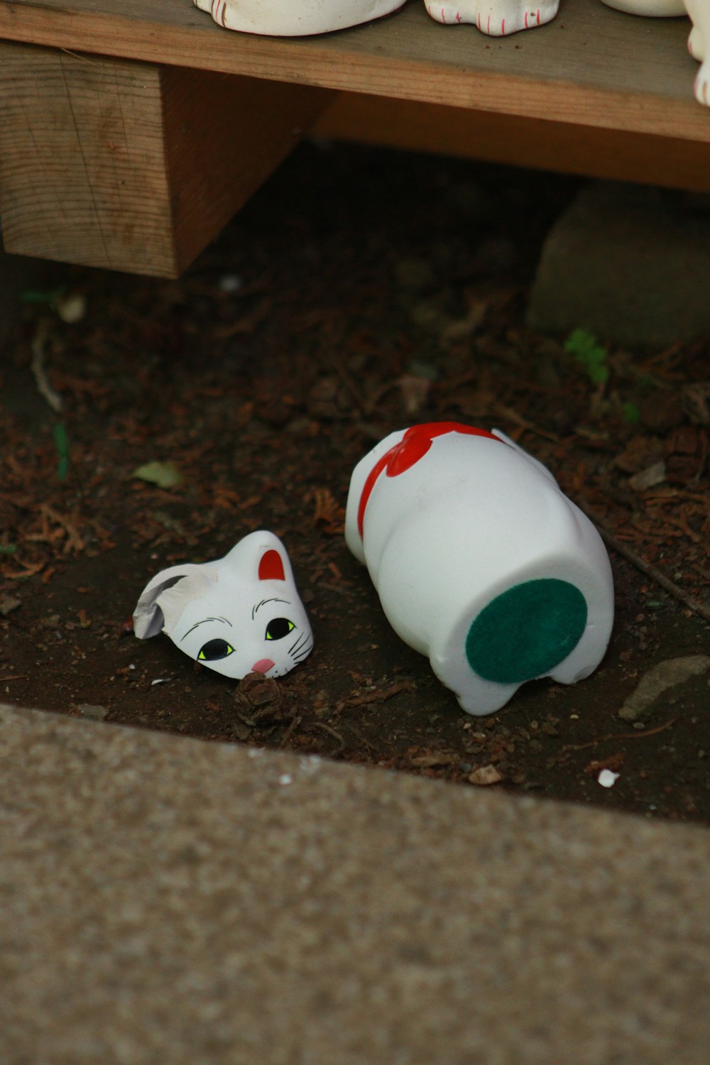 a white cat and a white cat figurine on the ground