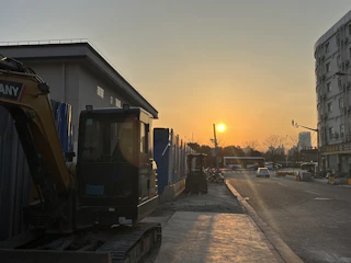 A modern construction waste container truck parked at a Riyadh construction site during sunset.