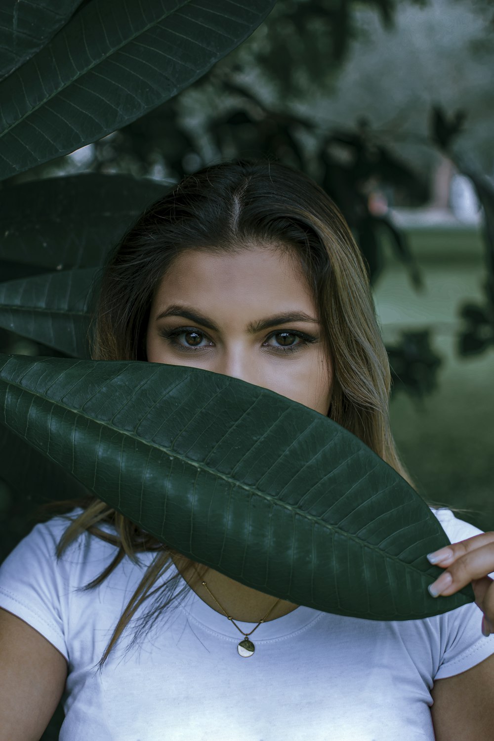 a woman holding a green leaf over her face