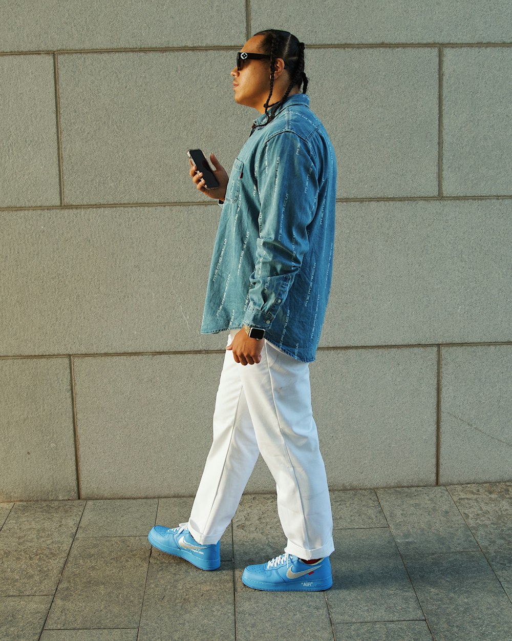 a woman walking down a sidewalk while looking at her cell phone