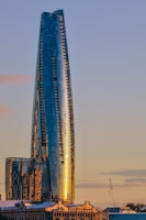 A sleek commercial office building with glass facades reflecting the city skyline at sunset.