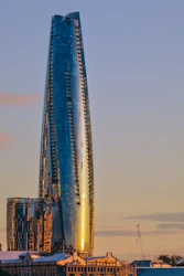 A sleek glass skyscraper with a subtle orange tint reflecting the vibrant Mumbai skyline.