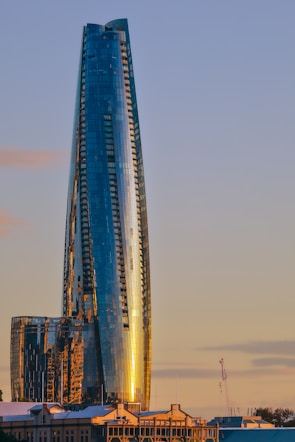 A sleek commercial office building with glass facades reflecting the city skyline at sunset.