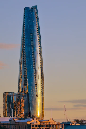 A sleek, modern Mumbai high-rise with maroon and beige accents glowing at sunset.