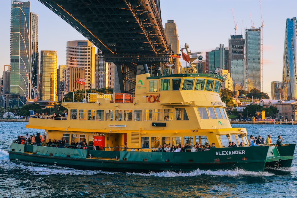 a yellow and green ferry boat under a bridge