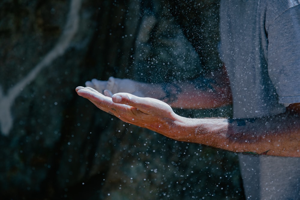 a man holding out his hand in the rain