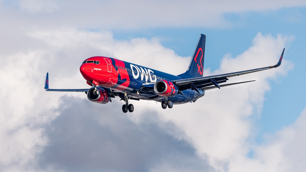 a red and blue plane is flying in the sky
