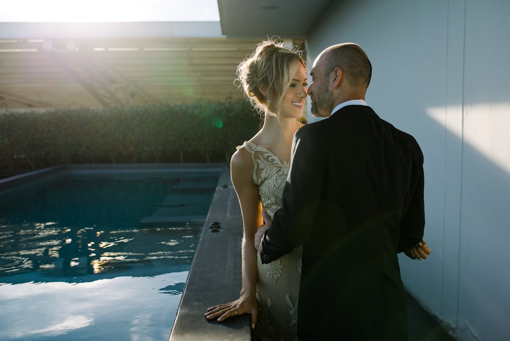 une mariée et un marié debout au bord d’une piscine