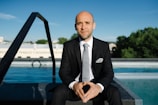a man in a suit and tie sitting in front of a pool