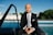 a man in a suit and tie sitting in front of a pool