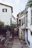 A quiet cobblestone alleyway lined with charming old buildings and flowering balconies.