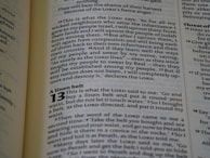 The image captures a page from an open book, likely a Bible, featuring prominently highlighted text in bold and large font, indicating chapter 13, titled 'A linen belt'. The surrounding text includes paragraphs of scripture in smaller font with several verses.