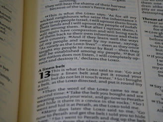 The image captures a page from an open book, likely a Bible, featuring prominently highlighted text in bold and large font, indicating chapter 13, titled 'A linen belt'. The surrounding text includes paragraphs of scripture in smaller font with several verses.