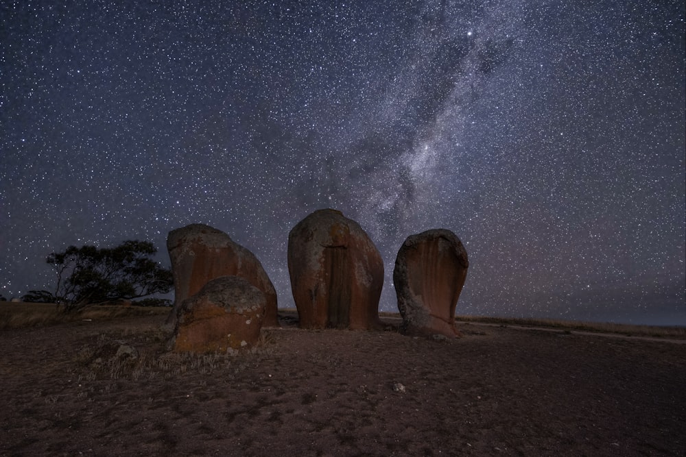 a group of rocks sitting on top of a dirt field under a night sky