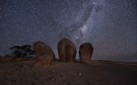 a group of rocks sitting on top of a dirt field under a night sky