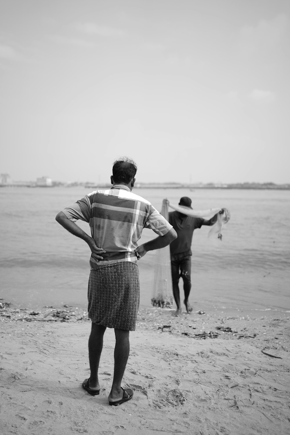 a man standing on top of a beach next to a body of water