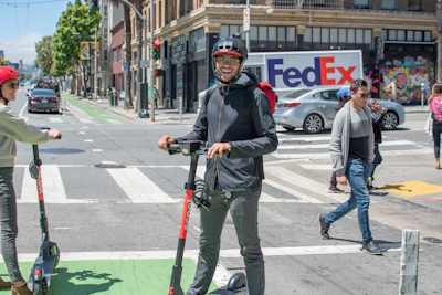 A happy customer riding an electric bike through a bustling Chennai neighborhood.