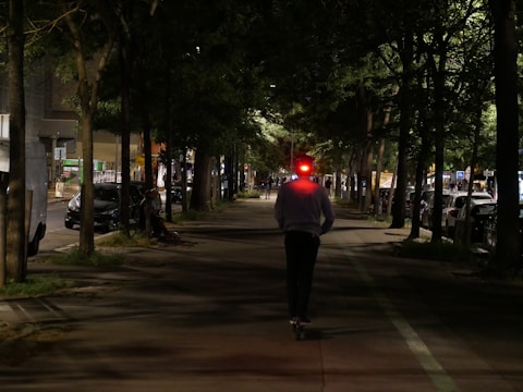 Red delivery scooter speeding through city streets during sunset.