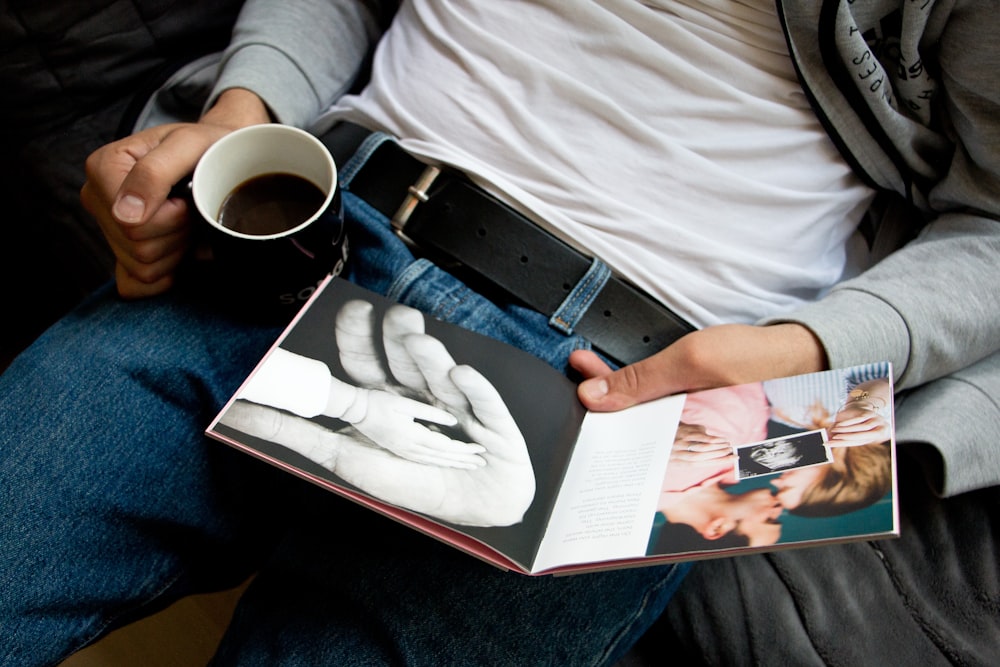 a person holding a book and a cup of coffee
