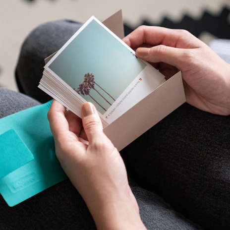 Customer holding a stack of glossy photo prints with a satisfied smile.