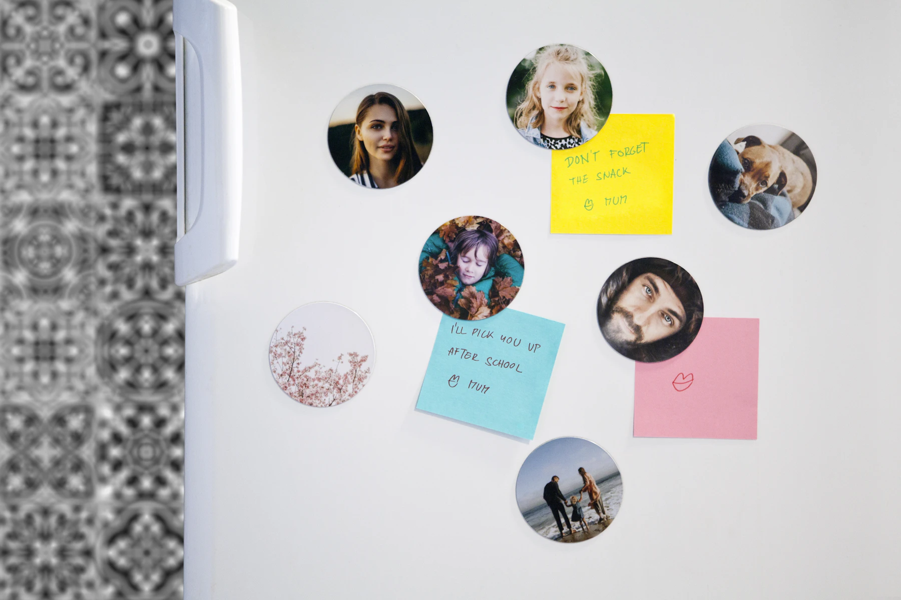 Round photo magnets and three handwritten sticky notes on a white fridge door