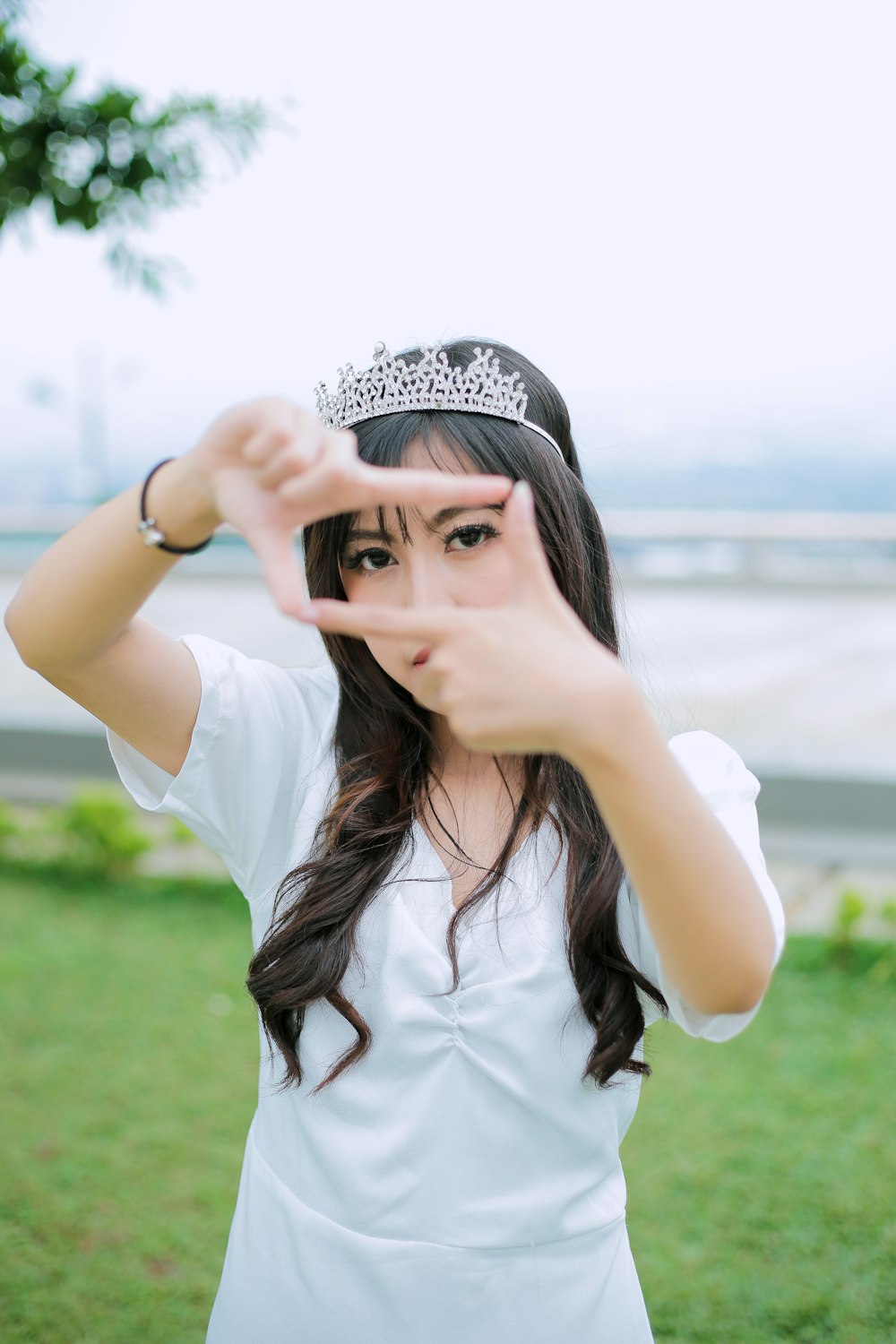 a woman wearing a tiara making a hand sign