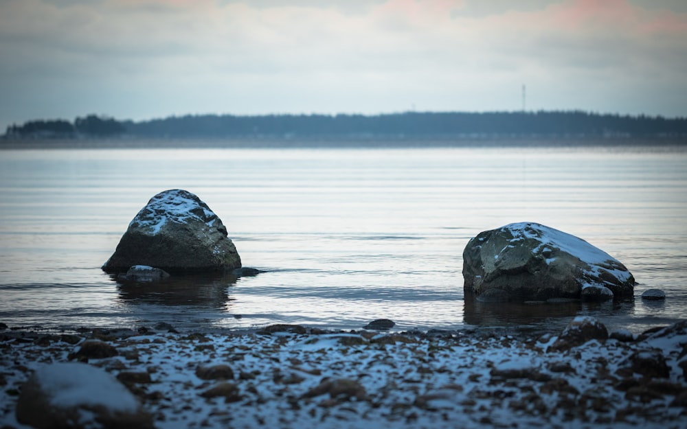 a couple of rocks sitting in the middle of a body of water
