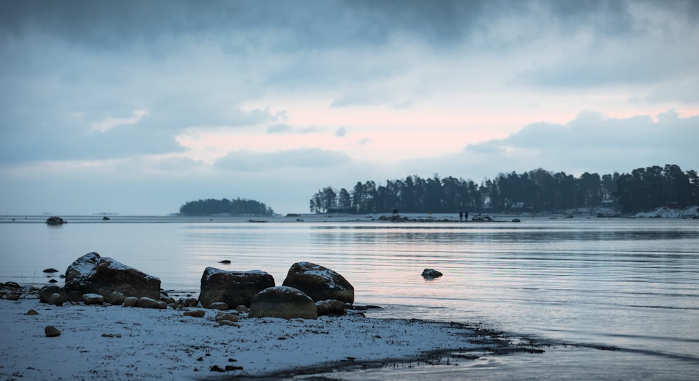 a body of water surrounded by snow covered rocks