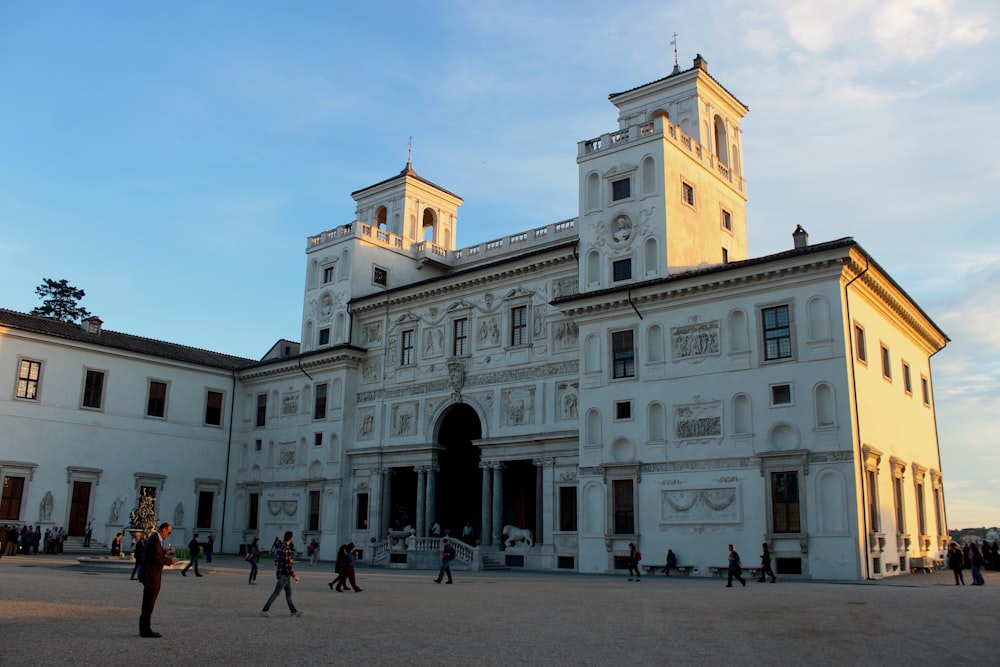 a group of people walking around a large white building