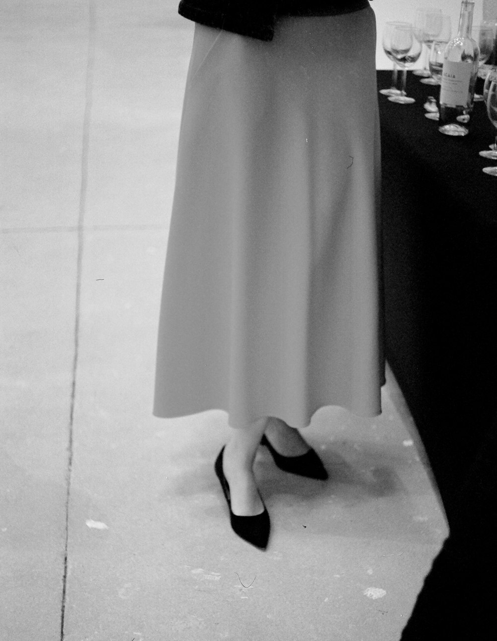 a woman standing next to a table with wine glasses