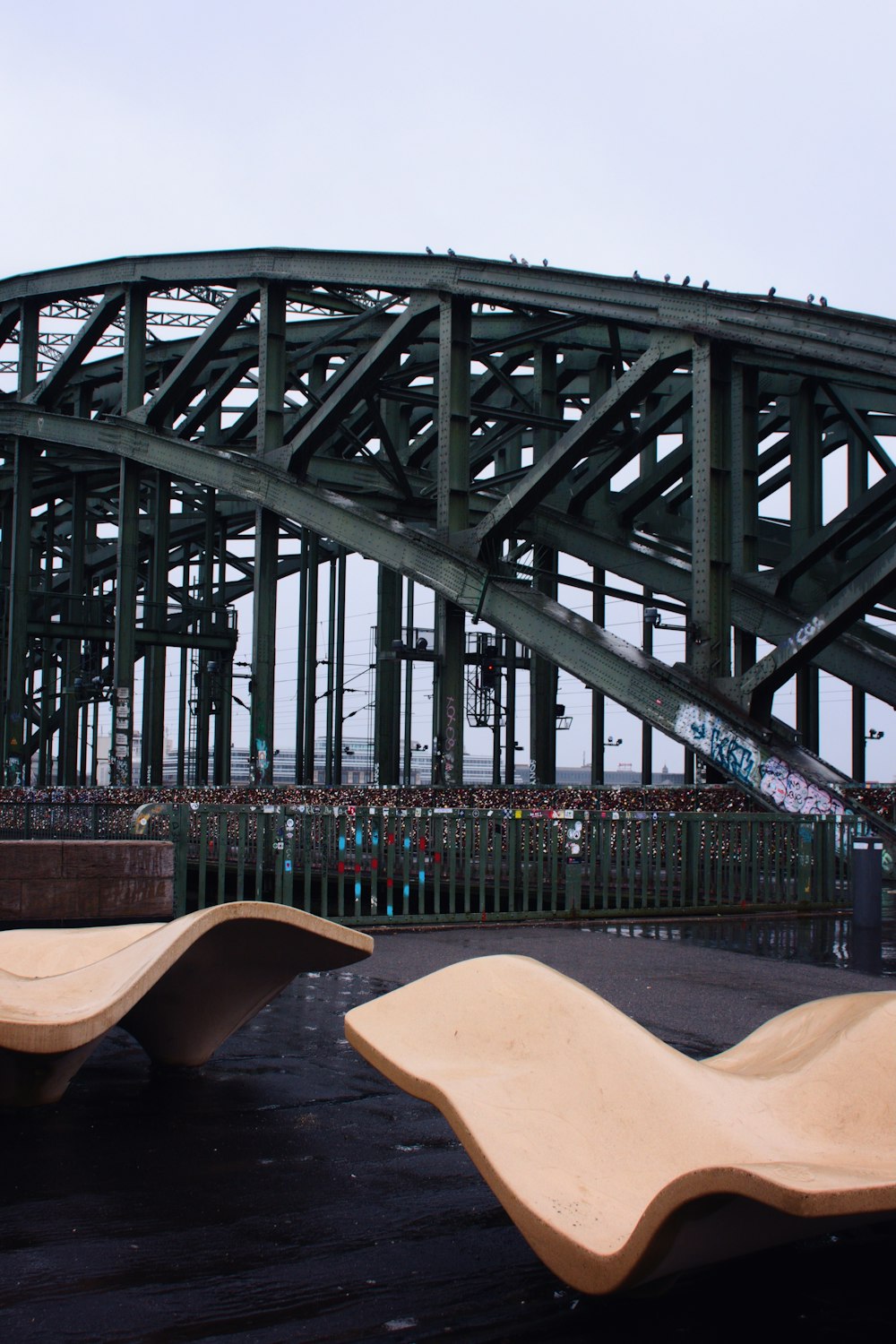 two wooden benches sitting in front of a bridge