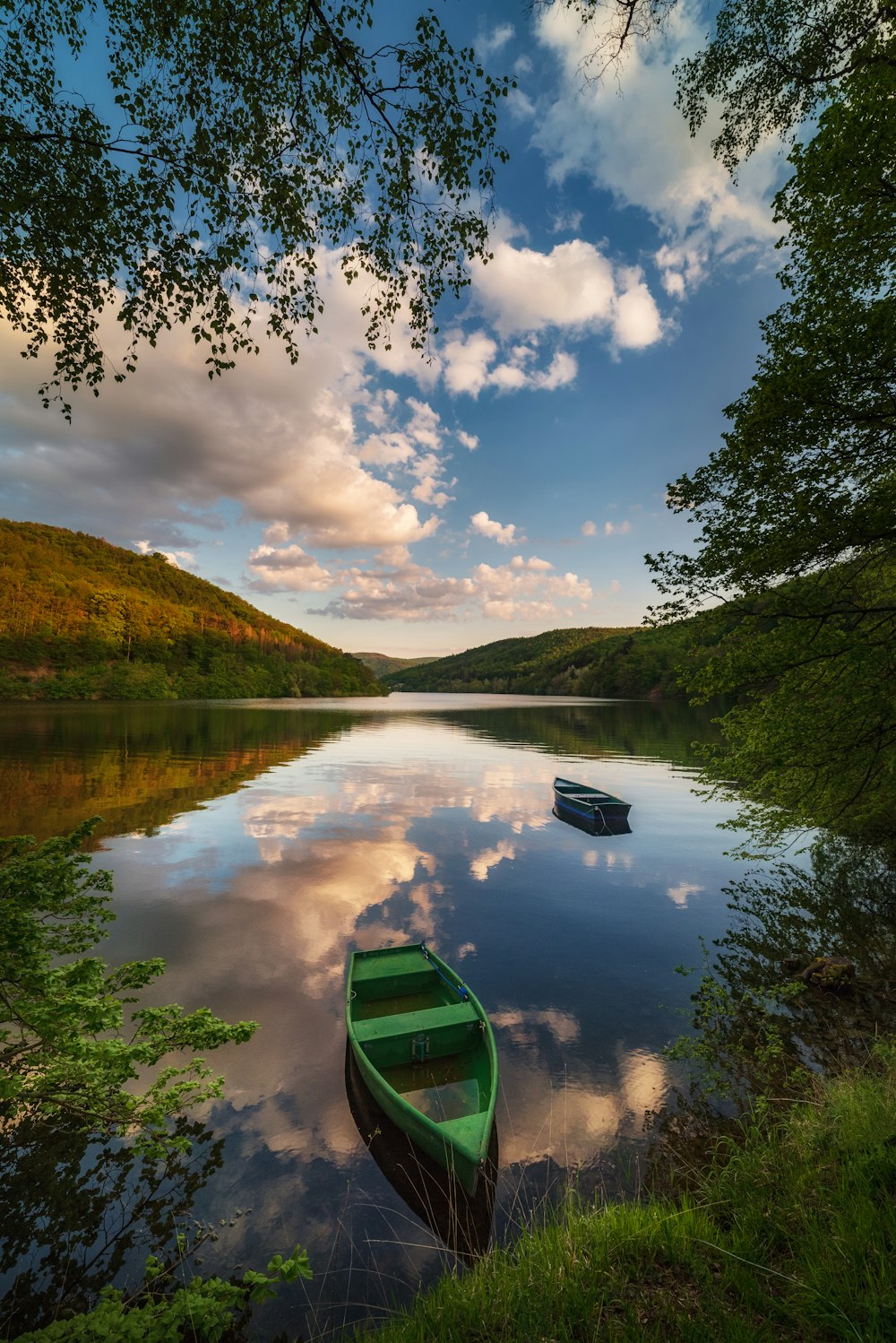 a green boat floating on top of a lake next to a forest