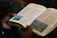 A smiling man holding a Christian book.