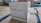 A white energy storage system labeled with 'HARVEYPOW' is situated in an industrial setting, surrounded by cardboard and wooden pallets. There is a green stripe on the unit with the words 'Energy storage system' beneath the brand name. The environment appears to be a warehouse.