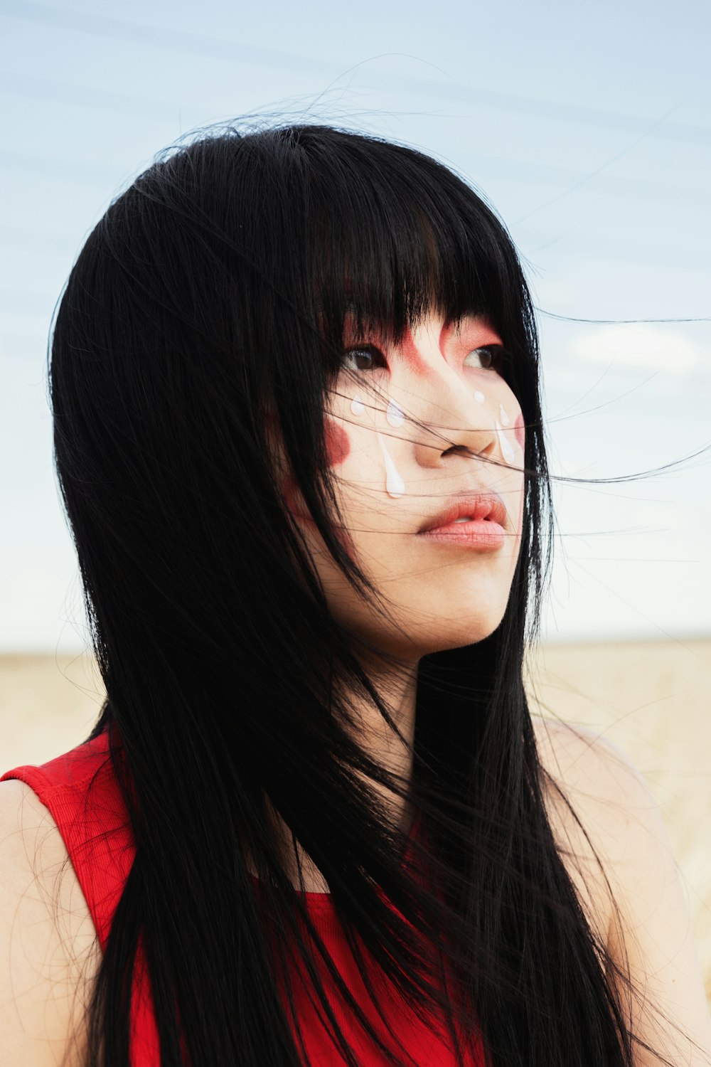 a woman with long black hair and white makeup