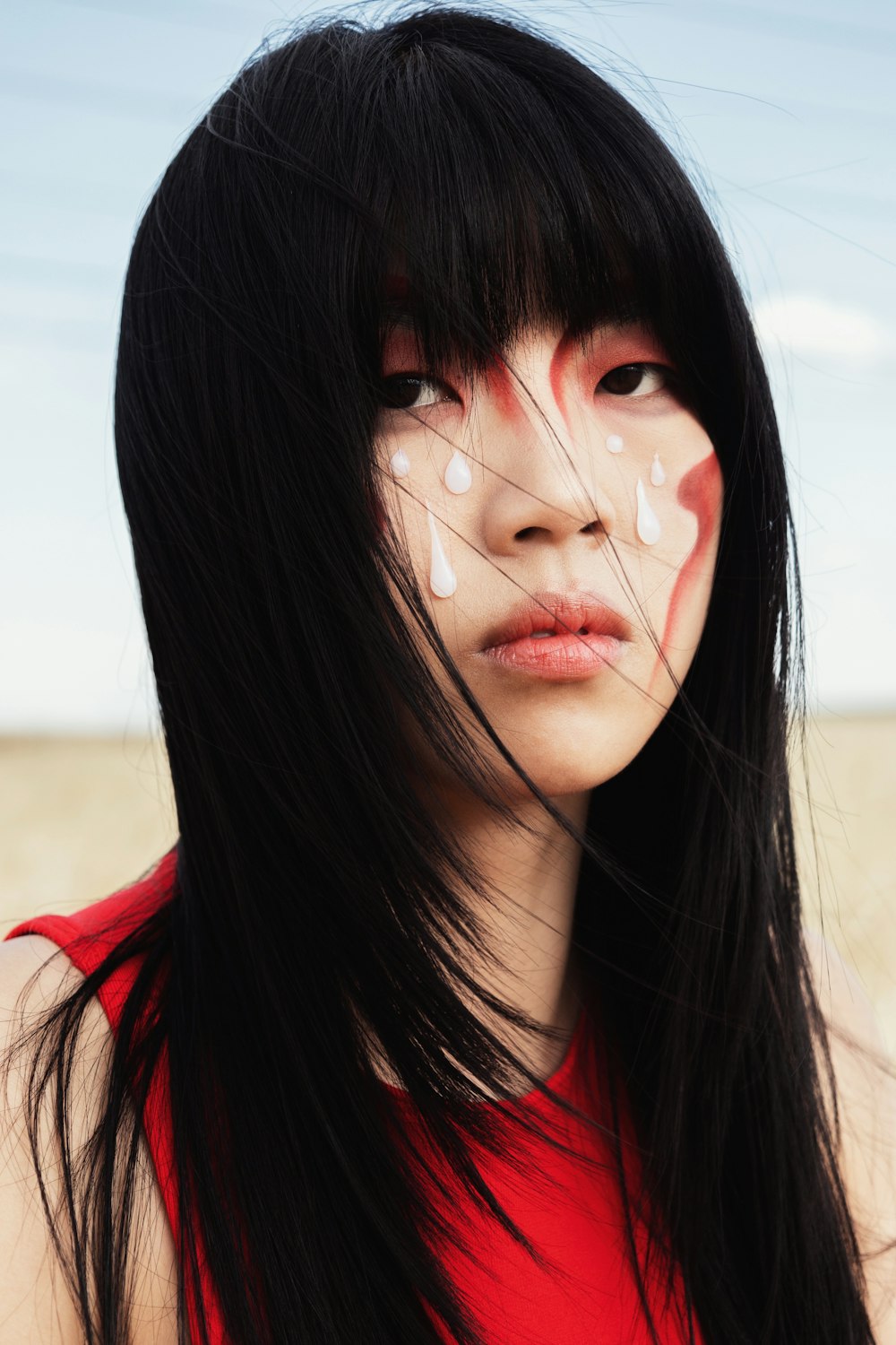a woman with long black hair and white paint on her face