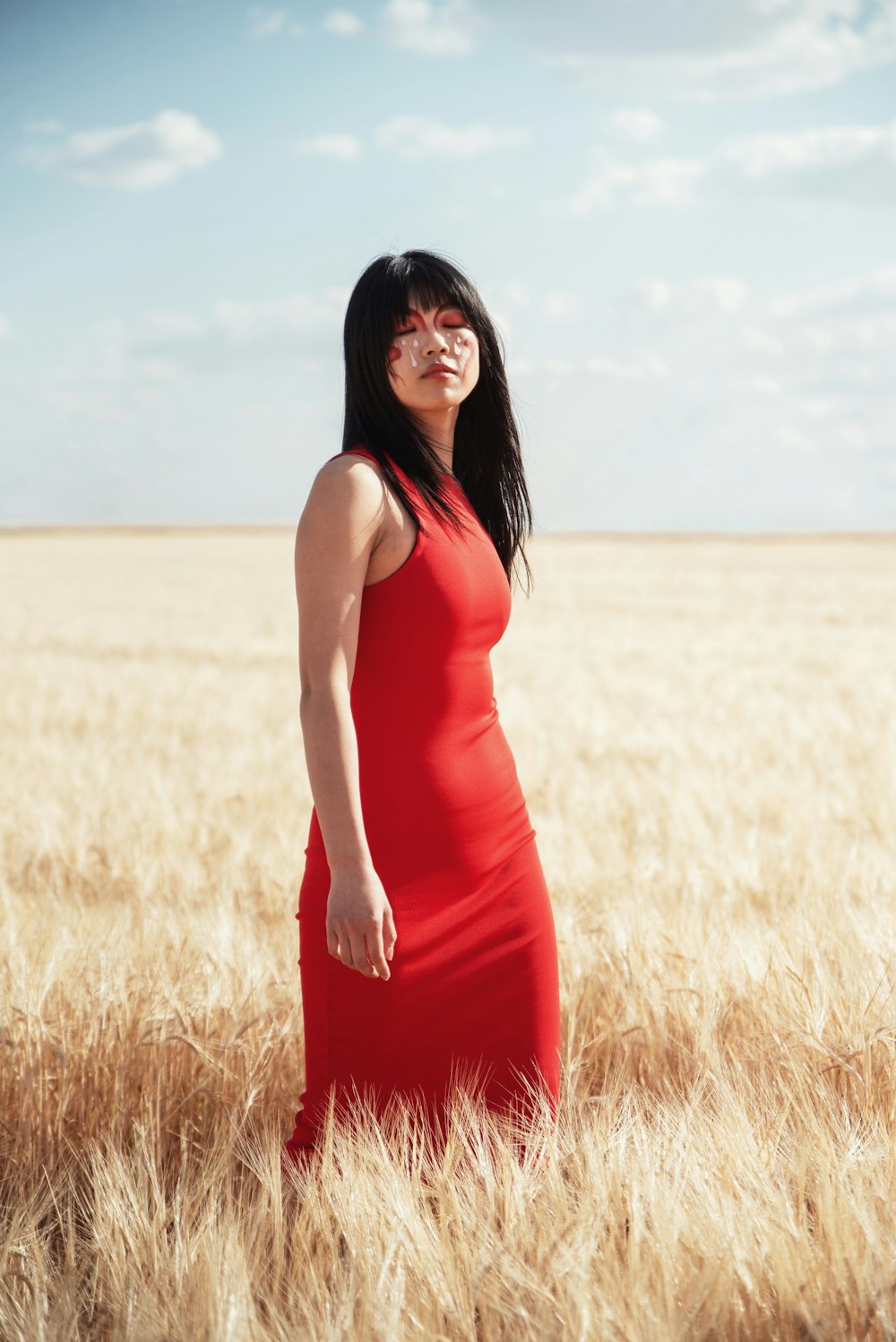 a woman in a red dress standing in a wheat field