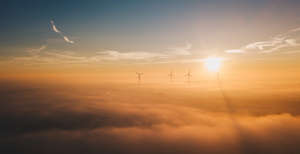 a group of windmills in the sky above the clouds