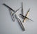 A collection of dental or engraving drill bits arranged on a smooth, light surface. These tools vary in size and shape, with metallic bodies and different colored rings near their tips for identification. Some have diamond or grit-coated tips, while others have a smooth finish, and one has a white conical shape.
