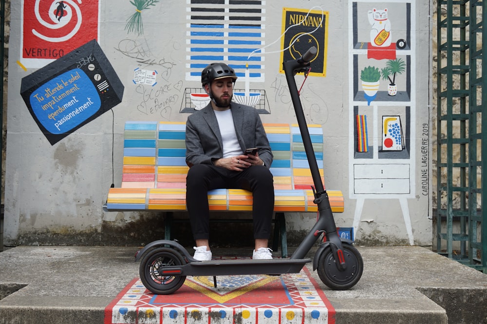 a man sitting on a bench next to a scooter