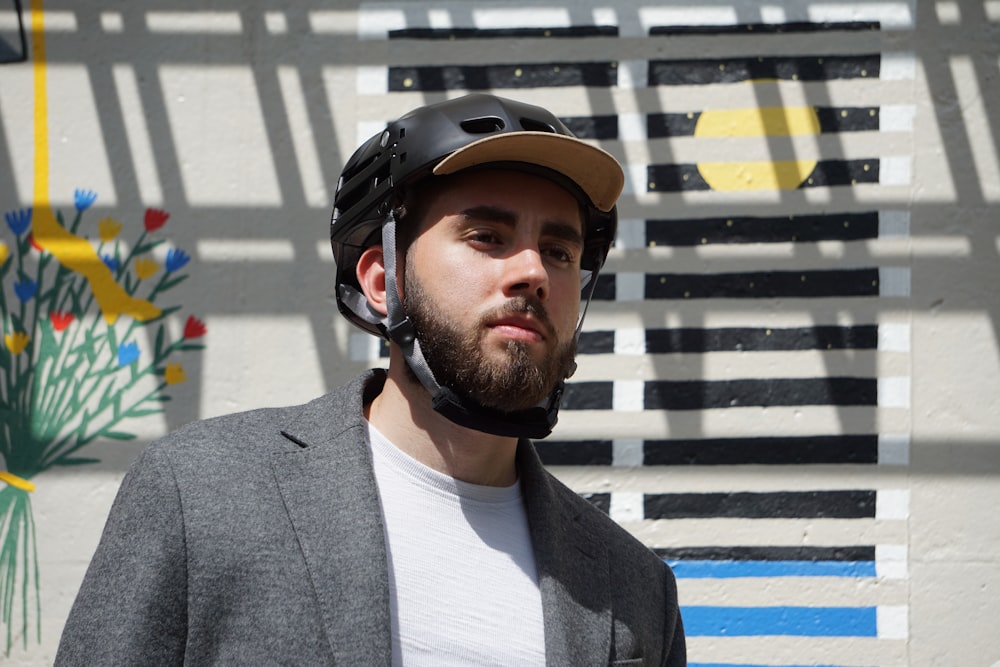 a man wearing a helmet standing in front of a wall