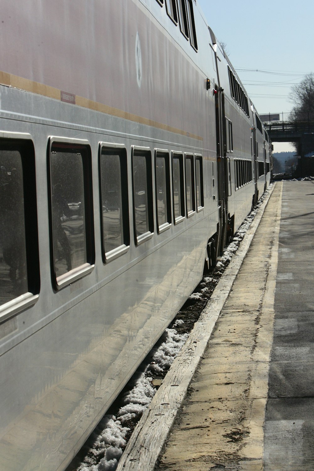 a silver train traveling down train tracks next to a platform