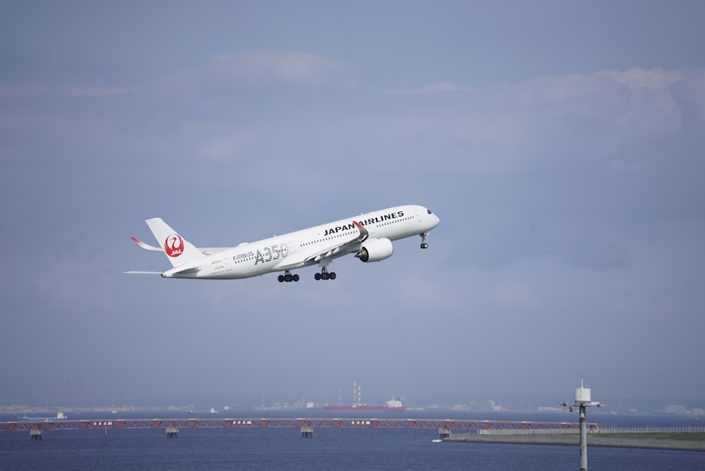 a large jetliner flying over a body of water