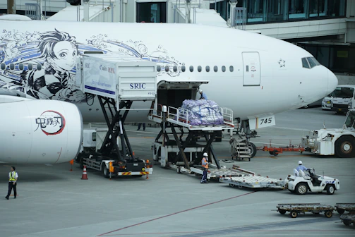 Ground service staff guiding passengers with luggage near an airplane on the tarmac.