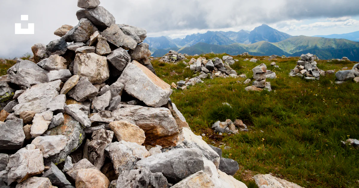 A pile of rocks sitting on top of a lush green field photo – Free Tatry ...