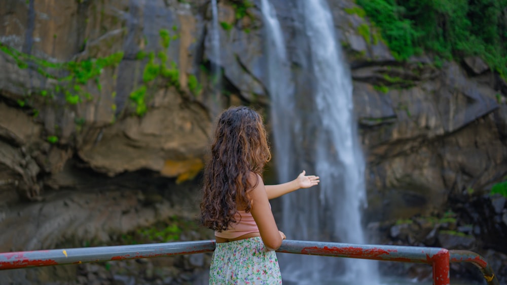 a little girl standing in front of a waterfall